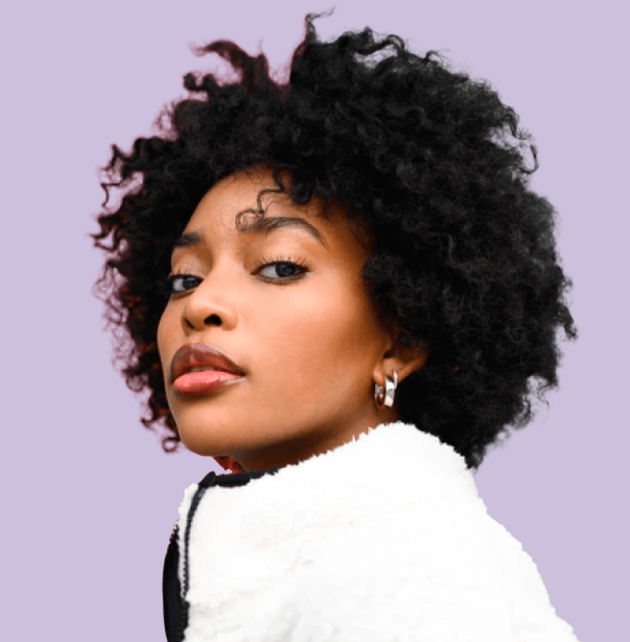 Woman with curly hair wearing a white jacket against a light purple background