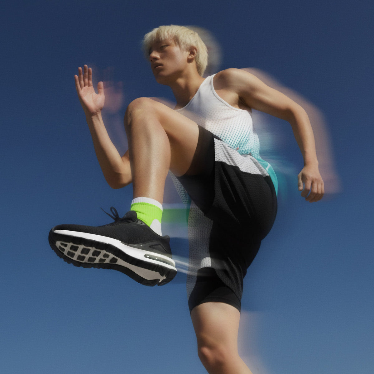 Person in athletic wear running against a blue sky (Green)