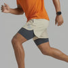 Person wearing a two-tone athletic outfit with beige shorts and an orange top on a white background (White)